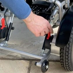 Person adjusting a component near the wheel of an electric wheelchair.