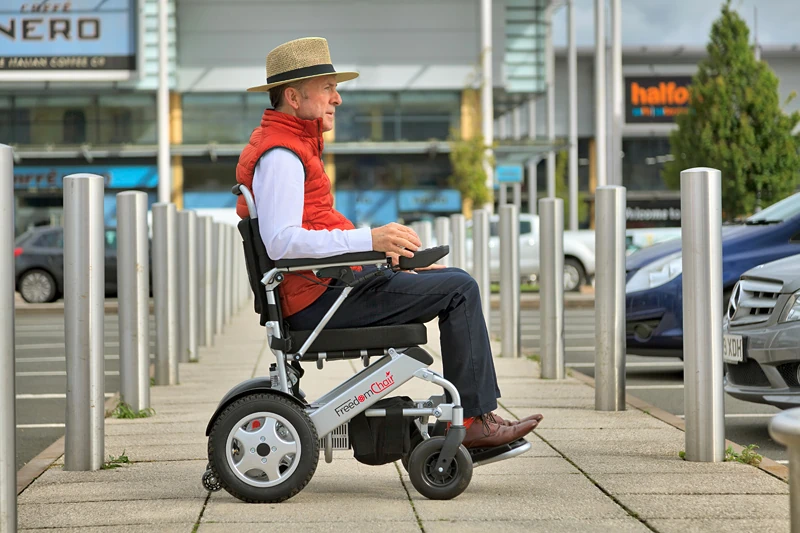 Person using Freedom Chair A06L electric wheelchair outdoors.