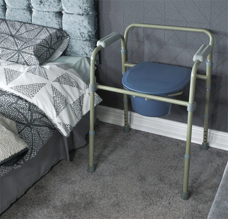 Bedside commode with adjustable legs next to a bed.