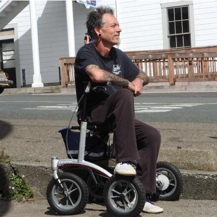 Person seated on a Trionic Walker Rollator outdoors.