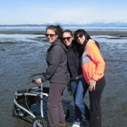 Three people with a Trionic Veloped Sport 12er rollator on a beach.