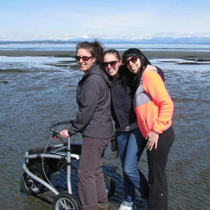 Three people with a Trionic Veloped Sport 12er rollator on a beach.