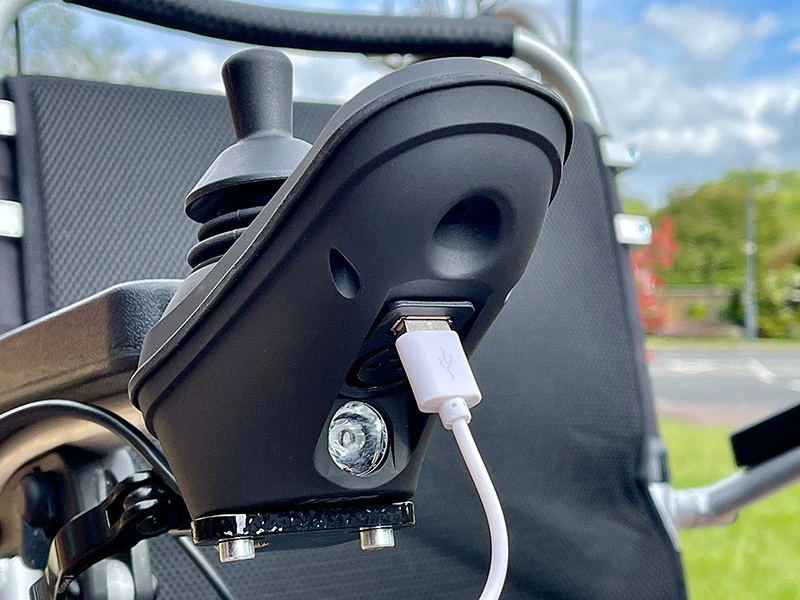 Close-up of joystick with USB charging port on an electric wheelchair.
