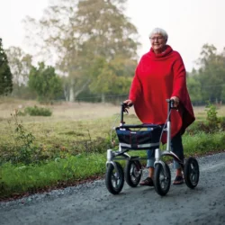 Person using a Trionic Walker Rollator on a gravel path outdoors.