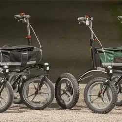 Two Trionic 14er Rollator Walkers with large wheels on a gravel path.