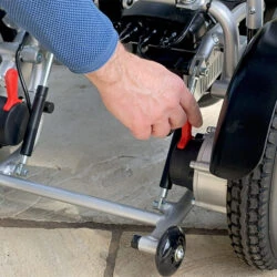 Close-up of a person adjusting the wheel mechanism on an electric wheelchair.