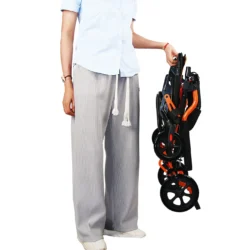 Person holding a folded lightweight travel wheelchair.