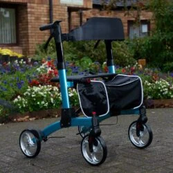 Blue folding rollator with seat and shopping bag in a garden setting.