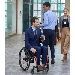 Man in a suit using a wheelchair in an office setting.