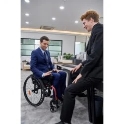 Two men in suits having a discussion, one seated in a power wheelchair.