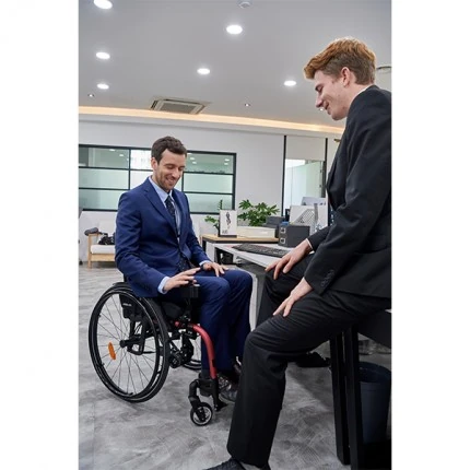 Two men in suits having a discussion, one seated in a power wheelchair.
