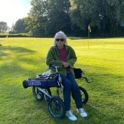Person seated on a Veloped Golf 14er rollator on a golf course.