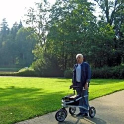 Person using a Rollator Veloped Tour 12er on a park path.