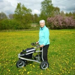 Person using Trionic Veloped Tour 14er rollator in a field of flowers.