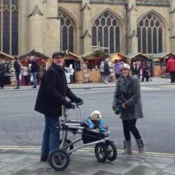 Two people with a dog using a Trionic Veloped Tour 14er in front of market stalls.