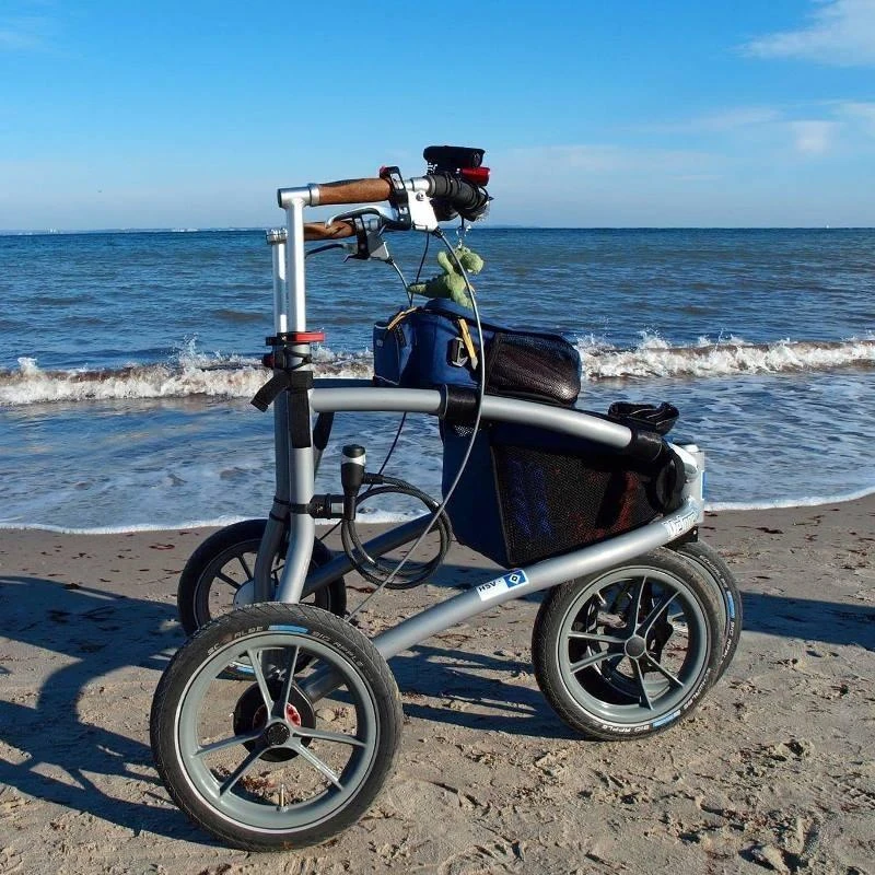 Trionic Veloped Trek 12er rollator on a sandy beach by the sea.
