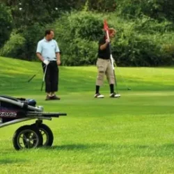 Veloped Golf 12er rollator parked on a golf course with golfers in the background.