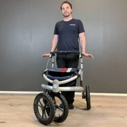Person standing behind a Trionic Veloped Trek 14er rollator.