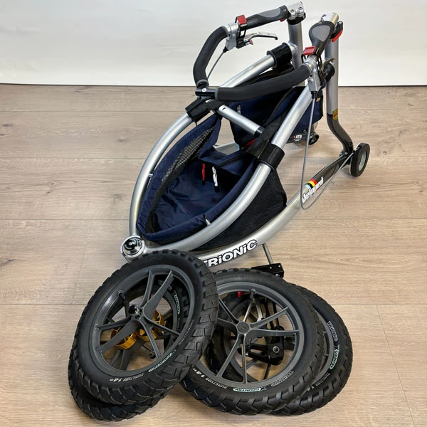 Folded Trionic Veloped Trek 12er with detached wheels on a wooden floor.