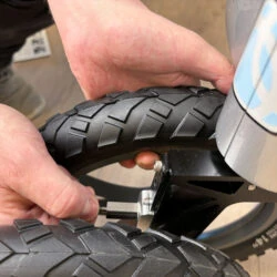 Hands adjusting the wheel of a Trionic Veloped Trek 14er rollator.