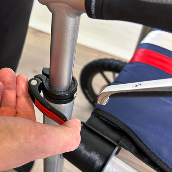 Close-up of a person adjusting the handle clamp on a Trionic Veloped Trek 12er rollator.