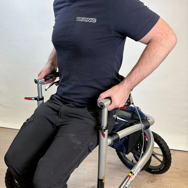 Person sitting on the Trionic Veloped Trek 14er rollator indoors.