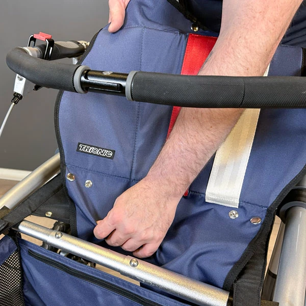 Person adjusting the seat of a Trionic Veloped Trek 12er rollator.