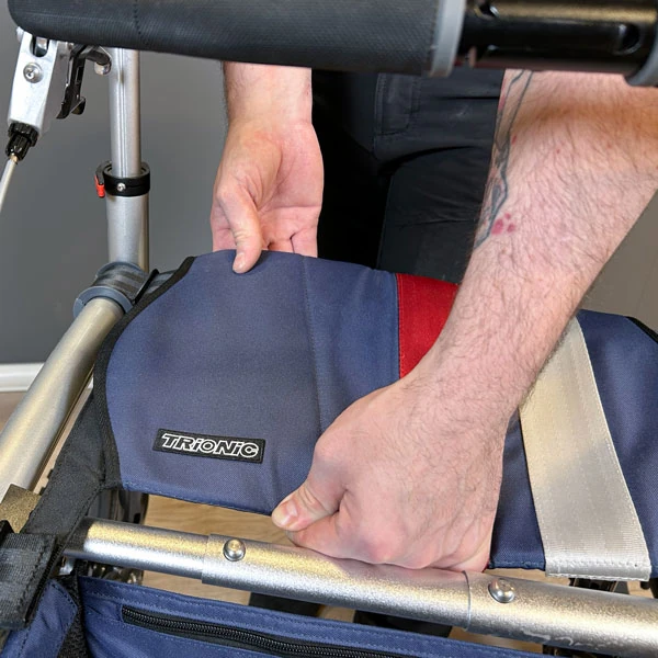 Person adjusting the seat of a Trionic Veloped Trek 12er rollator.