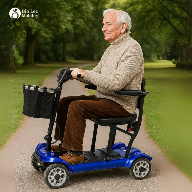 Person riding a blue foldable electric mobility scooter on a park path.