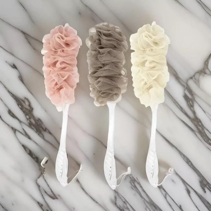 Three long handle bath brushes with soft mesh sponges in pink, brown, and cream.