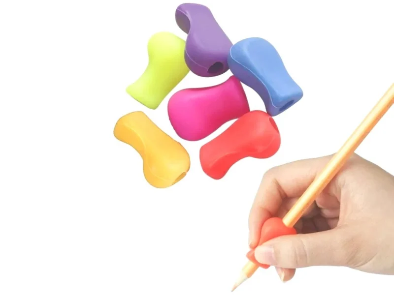 Six colorful pencil grips with a hand using one on a pencil.