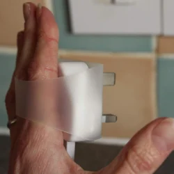 Hand using a Plug Tug to remove a plug from a socket.