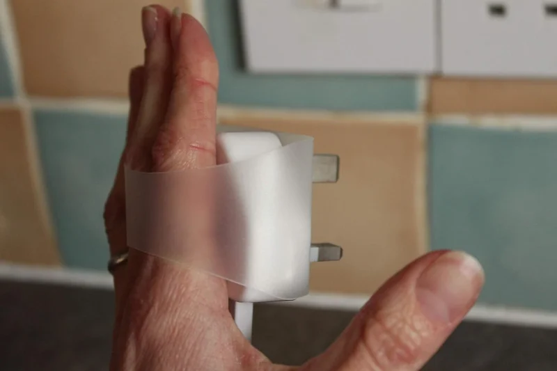 Hand using a Plug Tug to remove a plug from a socket.