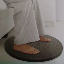 Feet standing on a black circular turntable with a textured surface.