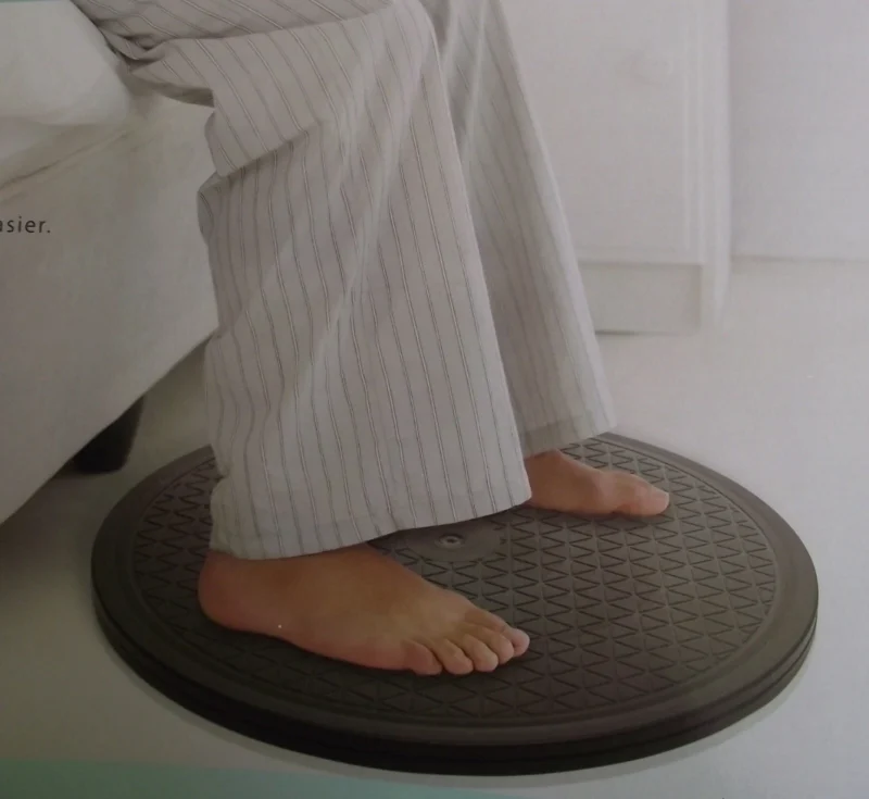 Feet standing on a black turntable with a textured surface.