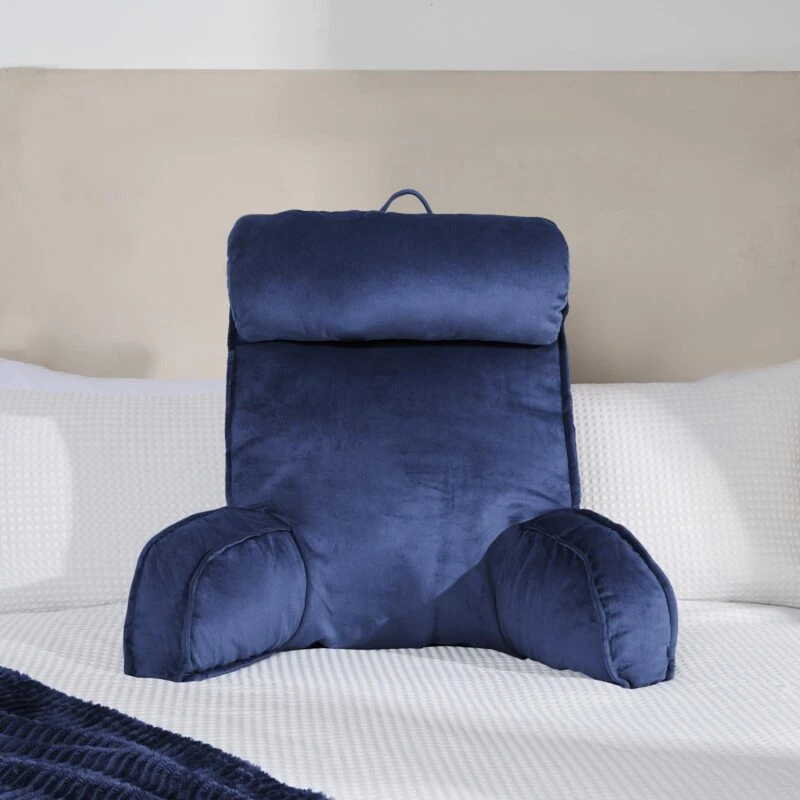 Navy lumbar support pillow on a white bed.