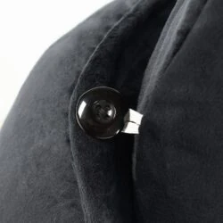 Close-up of a black button on a black velvet cushion.