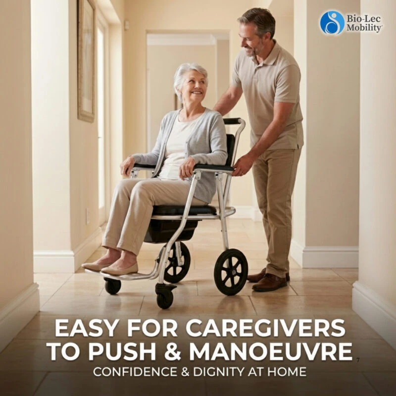 Caregiver pushing a person in a shower commode wheelchair in a hallway.