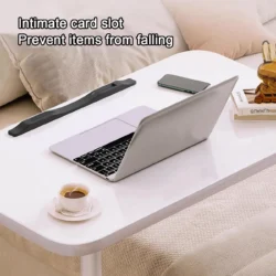 White over bed table tray with laptop, phone, and cup on top.