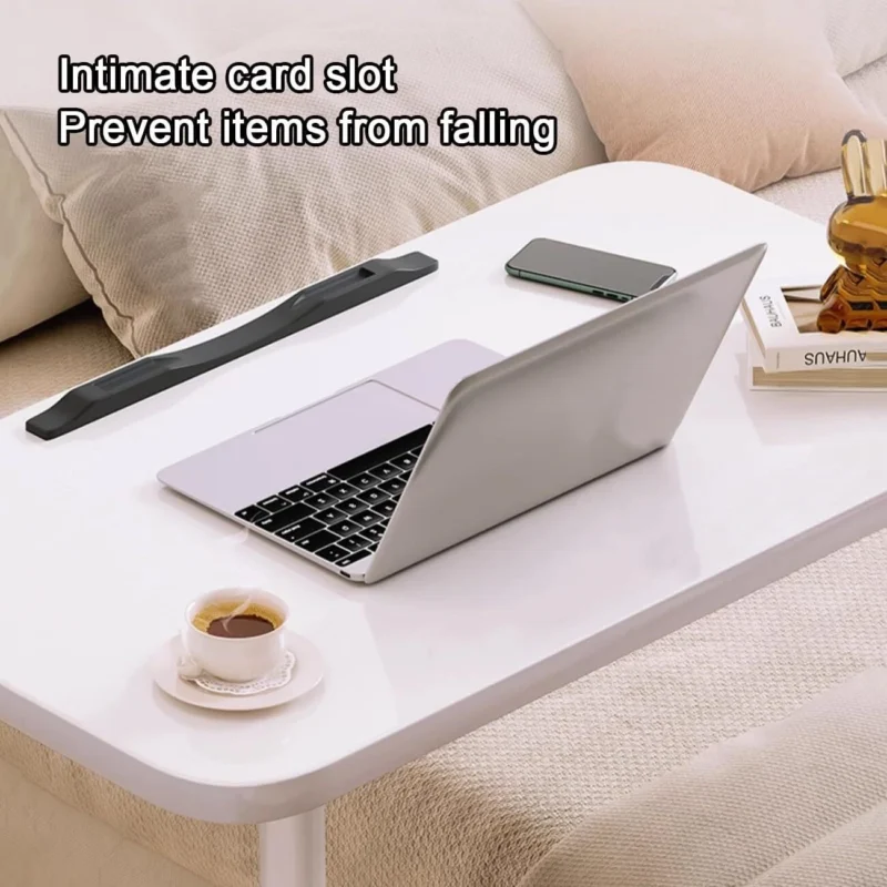 White over bed table tray with laptop, phone, and cup on top.