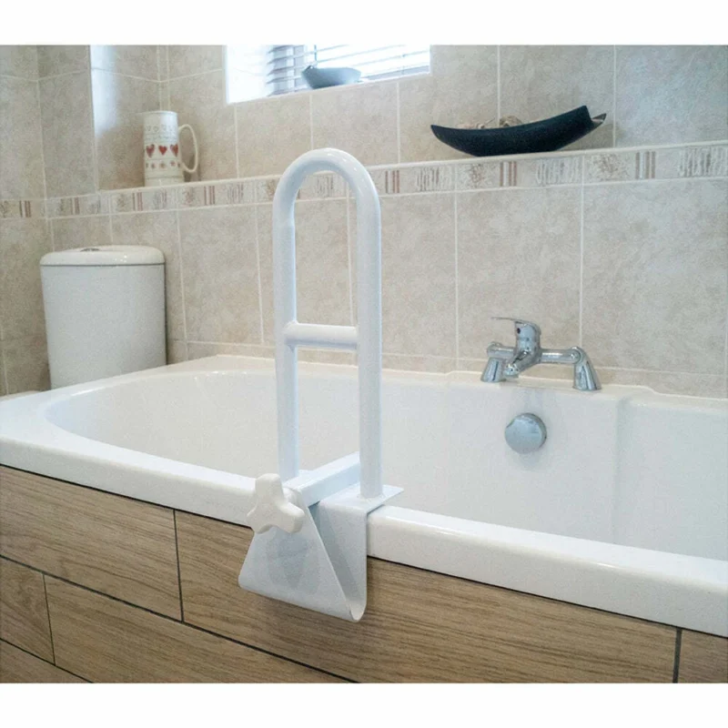 White removable grab bar attached to a bathtub edge in a bathroom.