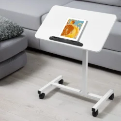 White over bed table with a tablet on top, next to a sofa.