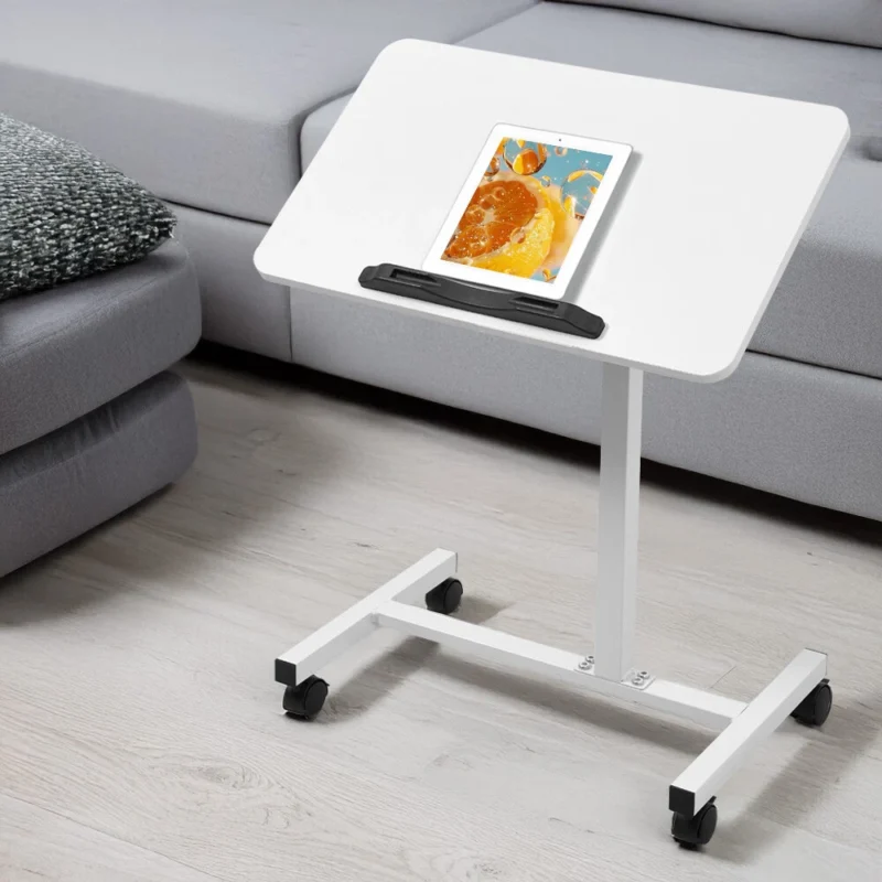 White over bed table with a tablet on top, next to a sofa.