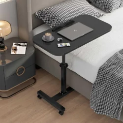 Black over bed table with laptop and coffee cup next to a bed.