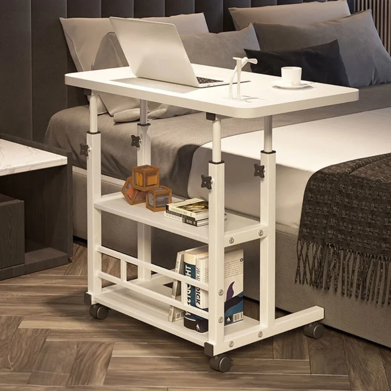 White over bed chair table with shelves, laptop, and books beside a bed.