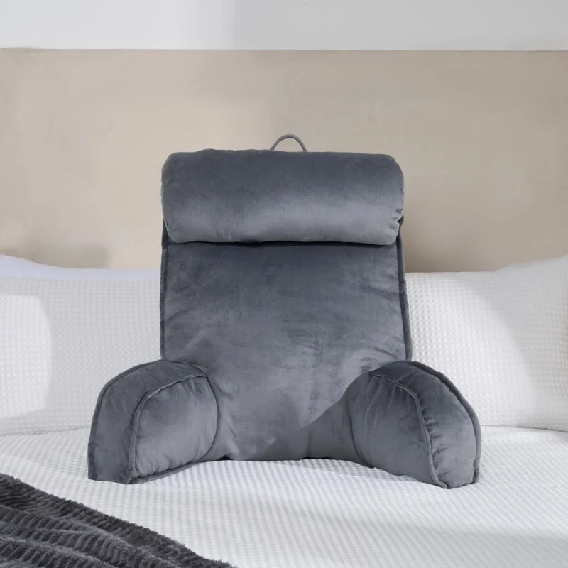 Grey lumbar support pillow on a bed with white bedding.