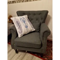 Dark grey tufted wingback armchair with a decorative pillow.