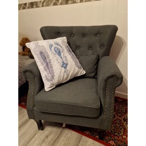 Dark grey tufted wingback armchair with a decorative pillow.
