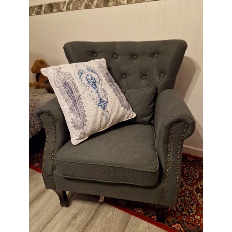 Dark grey tufted wingback armchair with a decorative pillow.