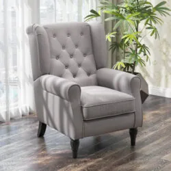 Grey wingback armchair with tufted back in a living room setting.